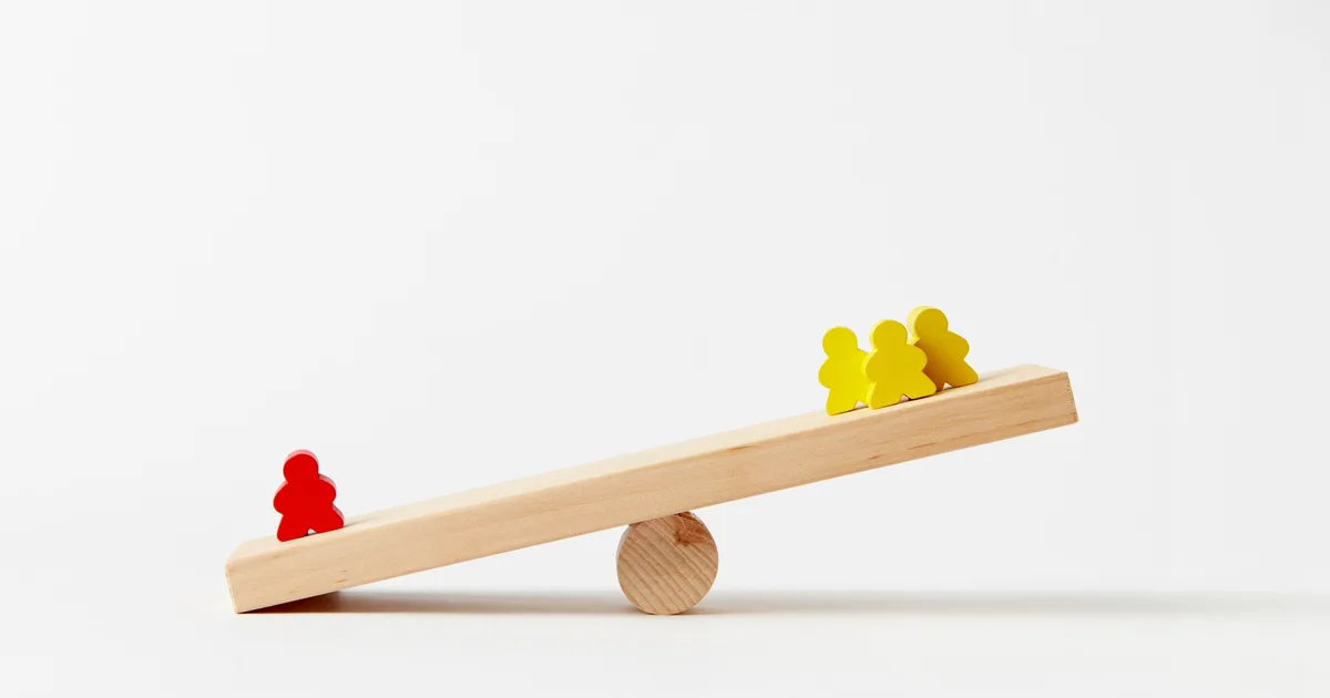 Bascule en bois avec un pion rouge d'un côté et trois pions jaunes de l'autre, sur fond blanc