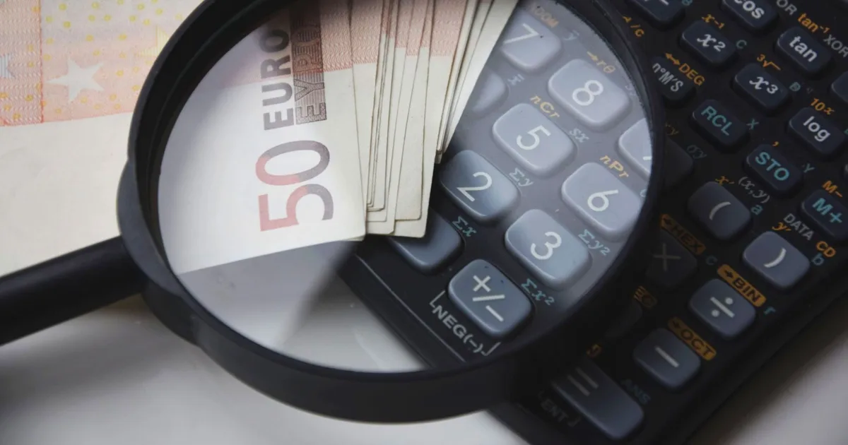 Loupe posée sur une liasse de billets de 50 euros et sur le clavier d'une calculatrice